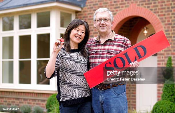 mature couple with new house keys - sold engels woord stockfoto's en -beelden