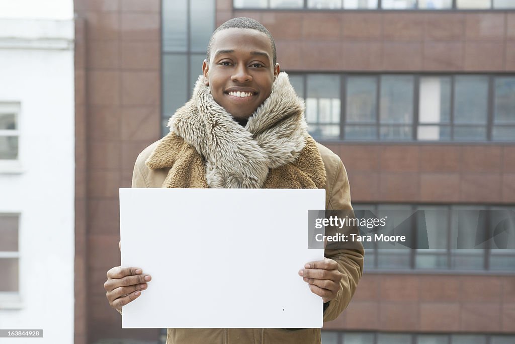 Young man smiling blank sign