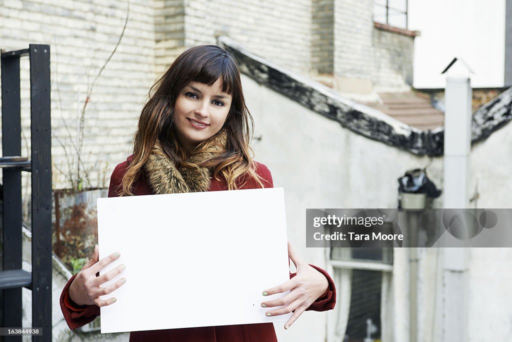 Young woman smiling holding blank sign