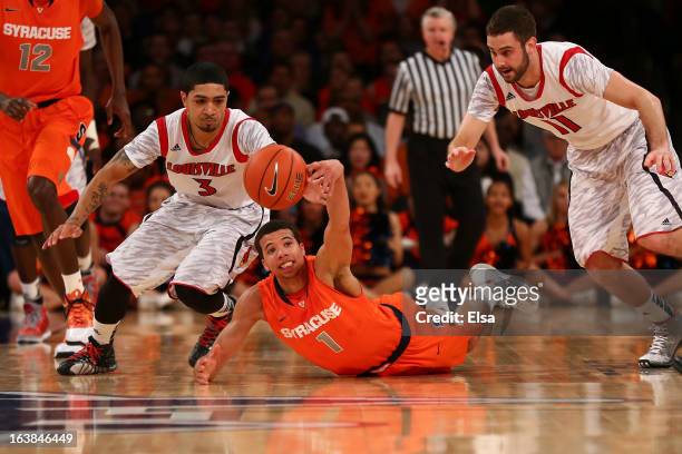 Michael Carter-Williams of the Syracuse Orange dives for a looseball against Peyton Siva and Luke Hancock of the Louisville Cardinals during the...