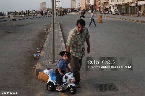 Libyan man and his son walk by the seaside promenade off Benghazi's Revolution Square on June 6, 2011 as news reports said Nato, confident that the...