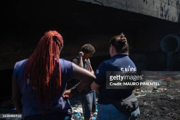 Social worker Silvana Amaral and physician Yasmine Nascimento speak with a homeless man inside a homeless encampment in the suburbs of Rio de...