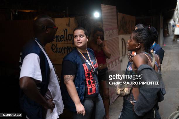 Nurse Quesia Ferreira talks to her colleagues and a patient during a visit of her Consultorio de Rua health team to a homeless encampment under a...