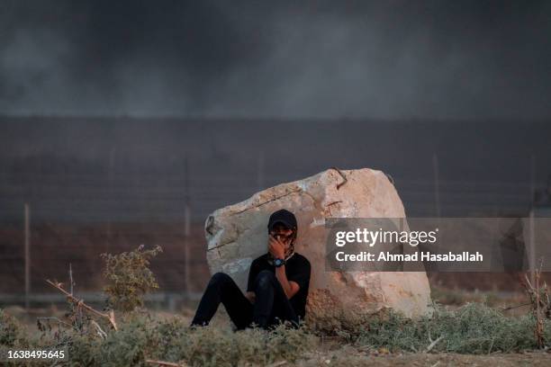 Palestinian protester sits behind a wall near the border fence between the Gaza Strip and Israel during a demonstration east of Gaza City against...