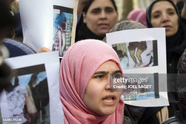 Protesters hold up photographs showing Libyan victims during a demonstration outside the Libyan consulate in Paris on February 22, 2011 in support of...