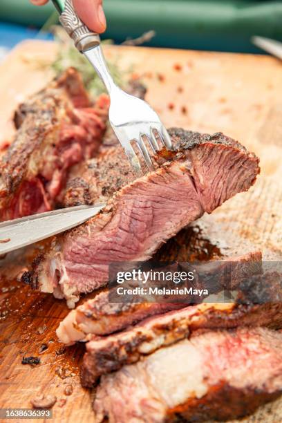 cutting bbq  meat entrecote filet beef steak into slices on wood copping board - entrecôte stockfoto's en -beelden