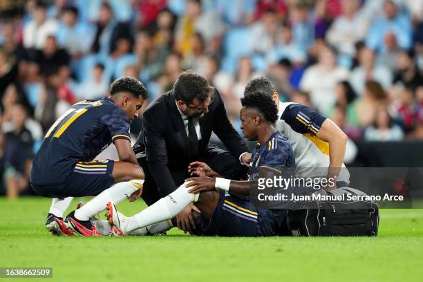 Vinicius Junior of Real Madrid receives medical treatment as he is checked on by teammate Rodrygo during the LaLiga EA Sports match between Celta...