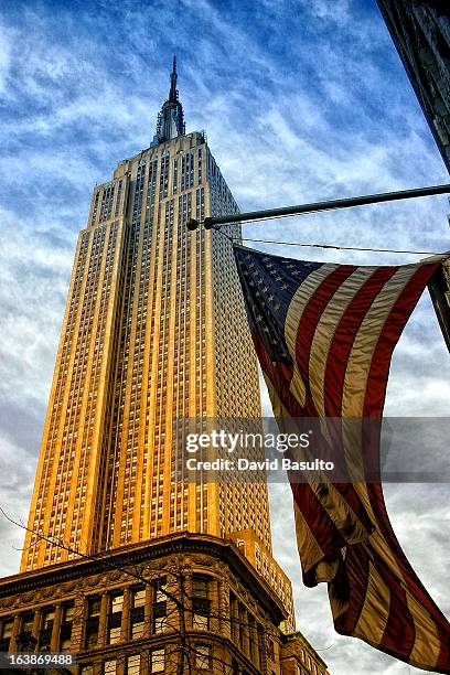 Bandera norteamerica en primer plano con el Empire state building de fondo.