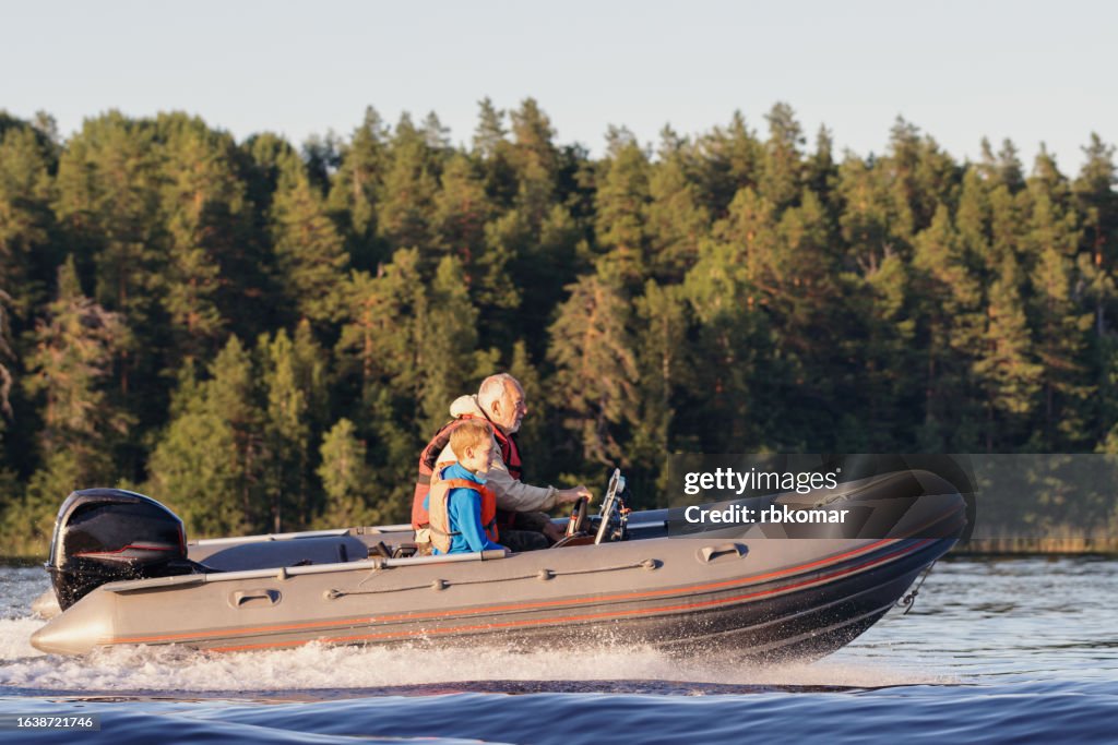 Speedboat with outboard engine - excited grandfather with grandson rushing through the water on the lake
