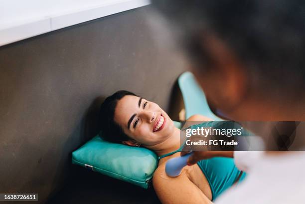 physiotherapeut massiert die schulter einer jungen frau in einem rehabilitationszentrum - sportmedizin stock-fotos und bilder