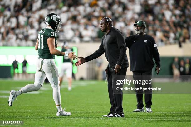 Michigan State Spartans head coach Mel Tucker greets long snapper Hank Pepper following an extra point during a college football game between the...