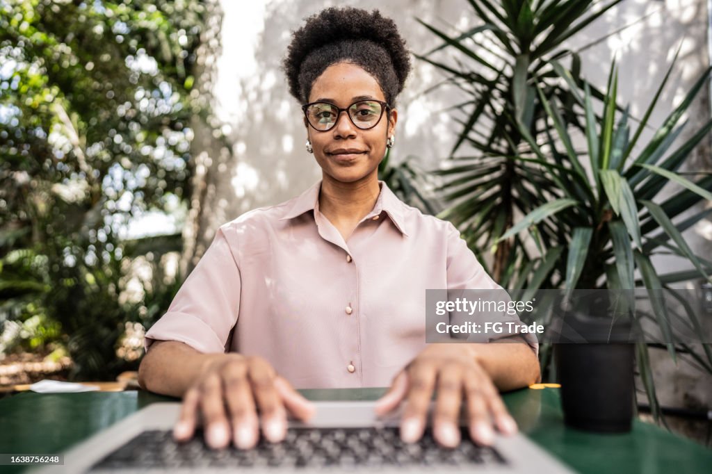 Retrato de uma jovem mulher de negócios usando laptop em uma cafeteria