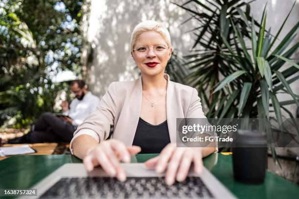 retrato de una mujer joven de negocios usando una computadora portátil en una cafetería - punto de vista de una cámara fotografías e imágenes de stock