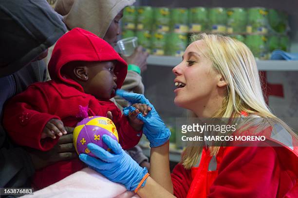 Volunteer of the Red Cross plays with a 8-month-old child at a Spanish Red Cross emergency services local in Tarifa, on March 17 after 32 would-be...