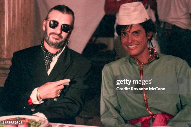 English singer, songwriter and actor and former Beatles drummer Ringo Starr sits next to an actor in coustume at a formal dining table on the set of...