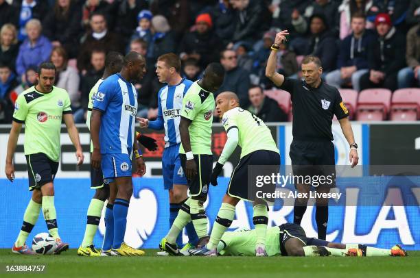 Referee Mark Halsey gestures to the bench as Massadio Haidara of Newcastle United lies injured during the Barclays Premier League match between Wigan...