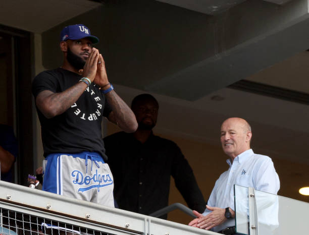 LeBron James of the Los Angeles Lakers waves to the crowd in front of President and CEO of the Los Angeles Dodgers Stan Kasten, during the game...