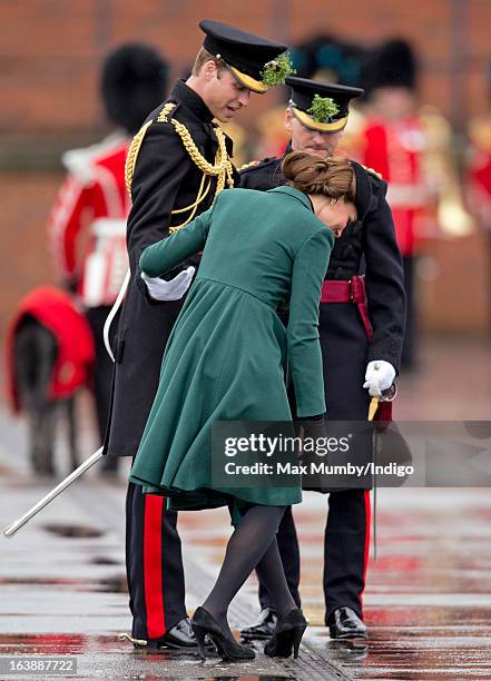 Prince William, Duke of Cambridge helps his wife Catherine, Duchess of Cambridge as she gets the heel of her shoe stuck in a grate as they attend the...