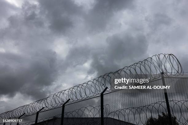 This photograph taken on August 28 shows a barbed wire fence displayed around a lorry parking in Marck, Northern France, to prevent migrants from...