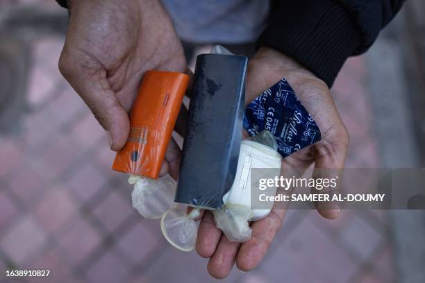 Migrant shows his passport and personal belongings inside condoms to protect them from water before trying to cross the English Channel to Britain in...