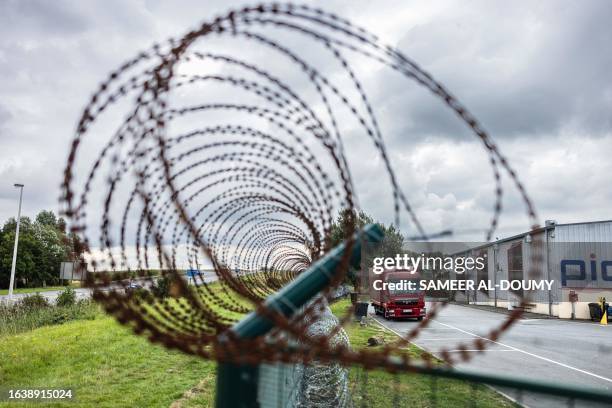 This photograph taken on August 28 shows a barbed wire fence displayed around a lorry parking in Marck, northern France, to prevent migrants from...