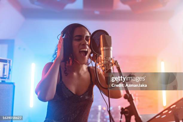 cantante femminile nera giovane adulta che canta appassionatamente nel microfono in uno studio di registrazione - leggio-per-spartiti-musicali foto e immagini stock