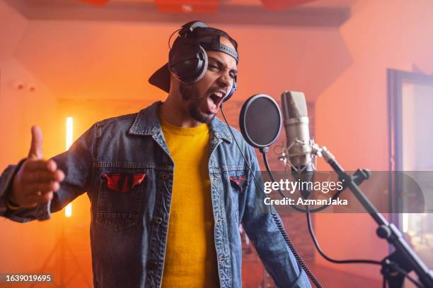 passionate young adult black male rap musician aggressively singing in a recording studio and moving his hands in a recording studio - nas rapper imagens e fotografias de stock