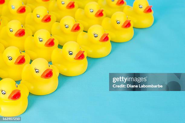 many rows of yellow rubber ducks on light blue background. - badeend stockfoto's en -beelden