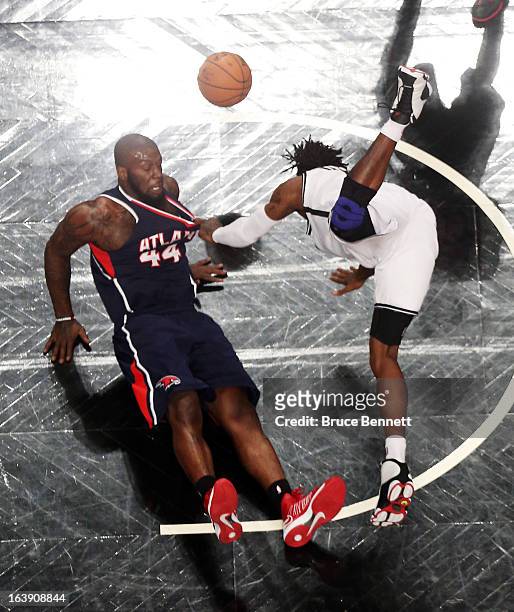 Ivan Johnson of the Atlanta Hawks and Gerald Wallace of the Brooklyn Nets hit the floor after colliding at the Barclays Center on March 17, 2013 in...