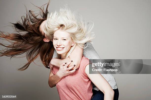 studio portrait of two women who are best friends - piggyback stock pictures, royalty-free photos & images