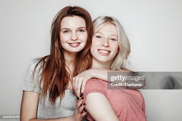 studio portrait of two women who are best friends - wange an wange stock-fotos und bilder