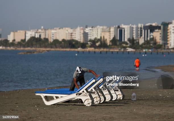 Man is seen cleaning sun loungers on the beach in Limassol, Cyprus, on Thursday, April 26, 2012. Europe braced for renewed turmoil as outrage in...