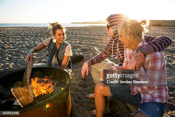 friends enjoying a beach bonfire. - bonfire beach stock pictures, royalty-free photos & images