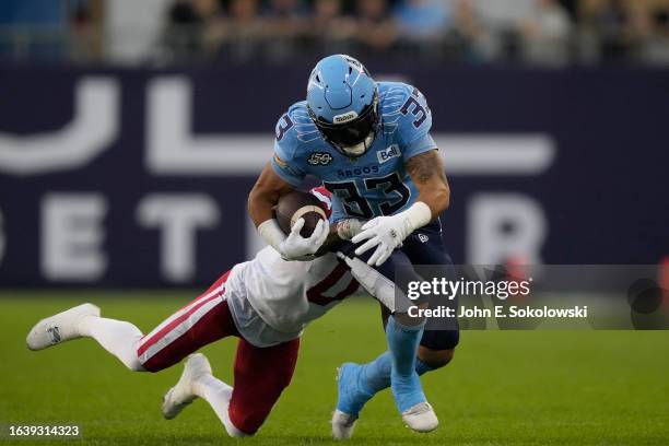Andrew Harris of the Toronto Argonauts tries to break a tackle from Kobe Williams of the Calgary Stampeders after a pass reception during the first...