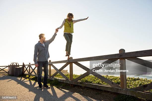 a couple balancing on a fence. - santa cruz california stock pictures, royalty-free photos & images
