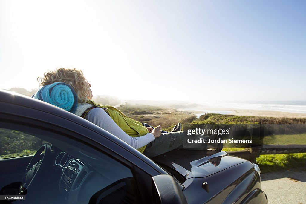 A female lying on the hood of a car.