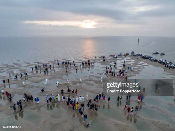 An aerial view at sunrise of the annual cricket match in the middle of The Solent, played on the Brambles sandbank which appears briefly at low tide,...