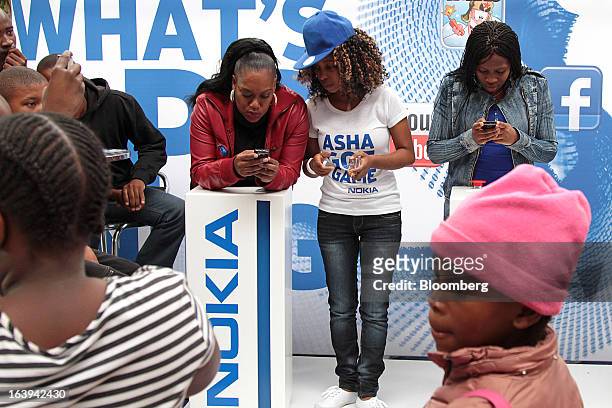 An employee demonstrates Nokia Asha smartphones to potential customers during a promotional "activation day" event by Nokia Oyj in Maponya Mall in...