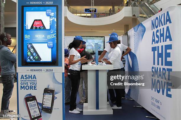 Employees promote new Nokia Asha smartphones to shoppers during a promotional "activation day" event by Nokia Oyj in Maponya Mall in Soweto, South...