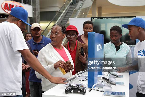 Employees demonstrate Nokia Asha smartphones to potential customers during a promotional "activation day" event by Nokia Oyj in Maponya Mall in...