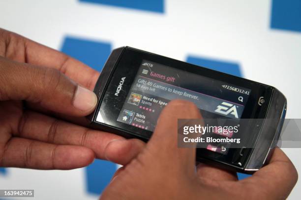 An employee demonstrates the function of a Nokia Asha 306 handset during a promotional "activation day" event by Nokia Oyj in Maponya Mall in Soweto,...
