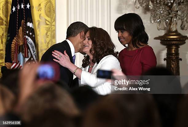 President Barack Obama hugs Amanda McMillan of Mississippi as first lady Michelle Obama looks on during a Women’s History Month Reception in the East...