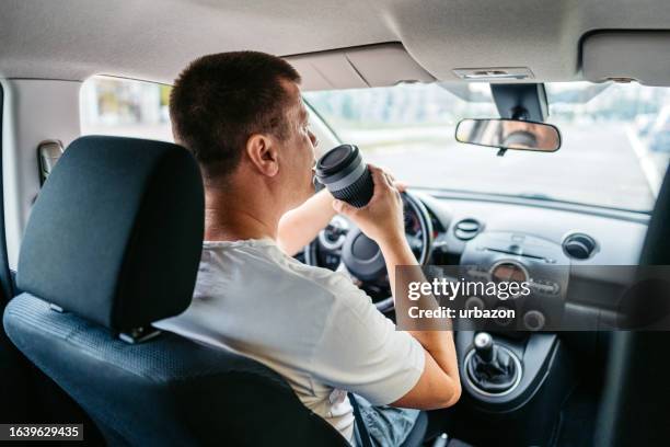 young man drinking coffee while driving a car - looking from rear of vehicle point of view stock pictures, royalty-free photos & images