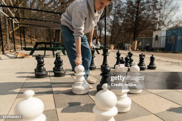 two teenage boys playing chess in city park - playing chess stockfoto's en -beelden