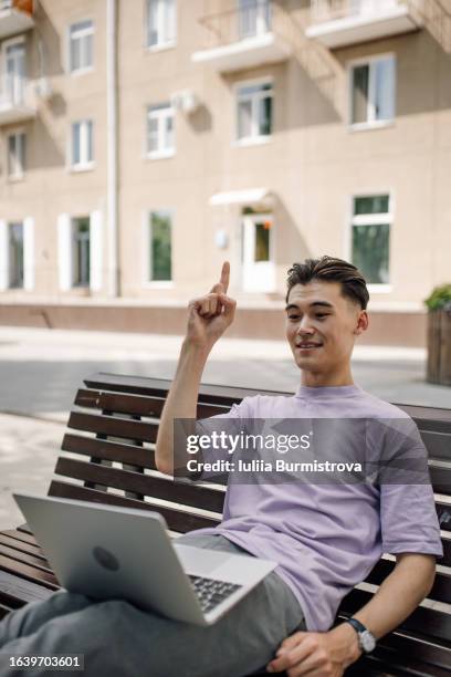 ambitious software engineer sitting on street bench with laptop on knees experiencing eureka moment - eureka moment stock-fotos und bilder