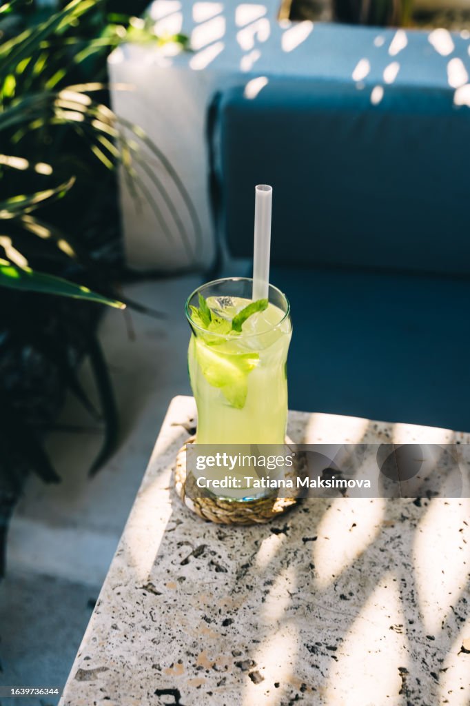 Mojito cocktail on the table in summer outdoor cafe. Sunset light.