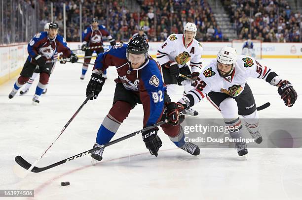 Gabriel Landeskog of the Colorado Avalanche controls the puck against Brandon Bollig of the Chicago Blackhawks at the Pepsi Center on March 18, 2013...