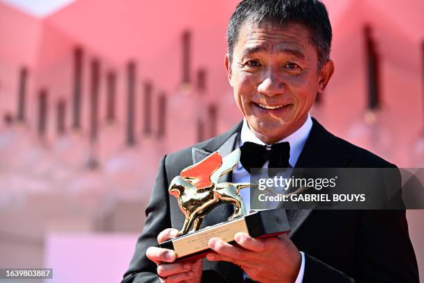 Hong Kong actor Tony Leung Chiu-wai poses on the red carpet after being awarded with the Golden Lion for Lifetime Achievement award at the 80th...