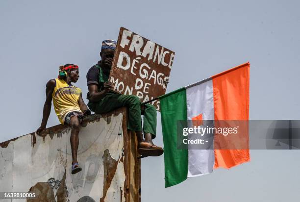 Man holds a placard and a Niger national flag as supporters of Niger's National Council of Safeguard of the Homeland protest outside the Niger and...