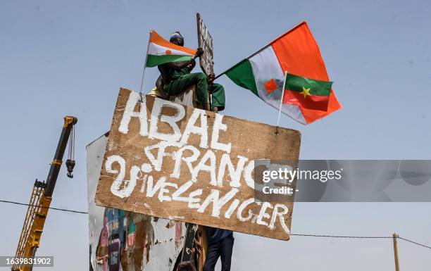 Man holds a placard as supporters of Niger's National Council of Safeguard of the Homeland protest outside the Niger and French airbase in Niamey on...